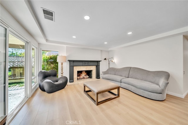 living room featuring a tile fireplace and light hardwood / wood-style floors