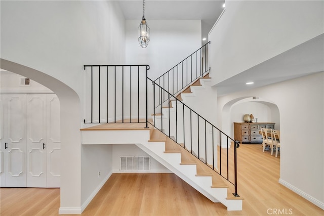 stairway featuring wood-type flooring and a notable chandelier