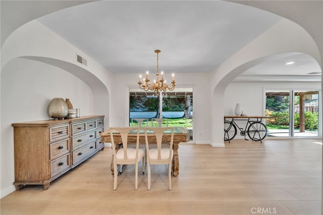 dining area with light hardwood / wood-style floors and a notable chandelier