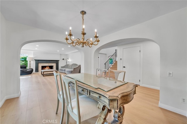 dining room with an inviting chandelier, light wood-type flooring, and a tiled fireplace