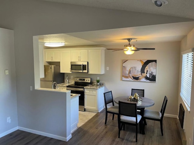 kitchen featuring vaulted ceiling, white cabinetry, appliances with stainless steel finishes, and dark wood-type flooring