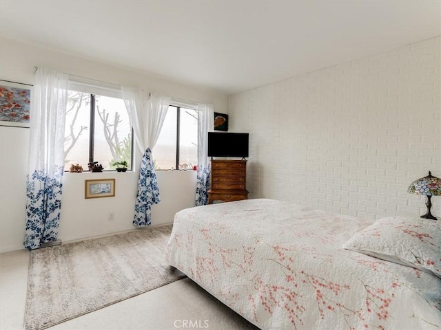 bedroom featuring brick wall and carpet floors