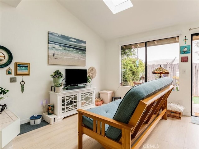 sitting room with lofted ceiling with skylight and light wood-style flooring