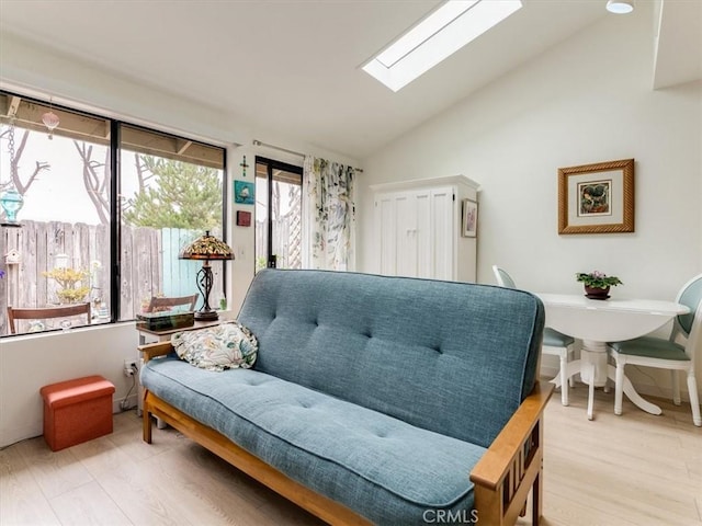 interior space featuring lofted ceiling with skylight and light wood-style floors