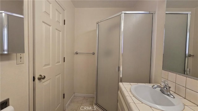 full bath with a sink, tasteful backsplash, and a shower stall