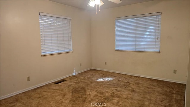 carpeted spare room with baseboards, a ceiling fan, and visible vents
