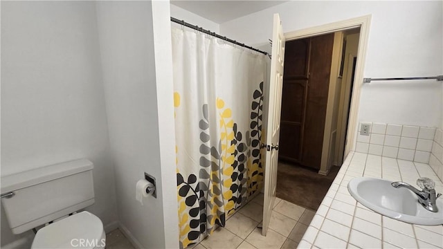 full bath with toilet, tile patterned floors, curtained shower, and a sink