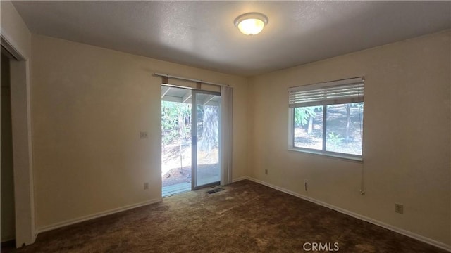 unfurnished room with a healthy amount of sunlight, baseboards, carpet, and visible vents