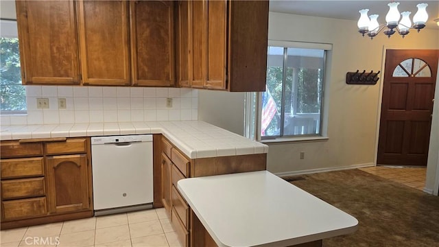 kitchen with tasteful backsplash, a wealth of natural light, an inviting chandelier, and dishwasher