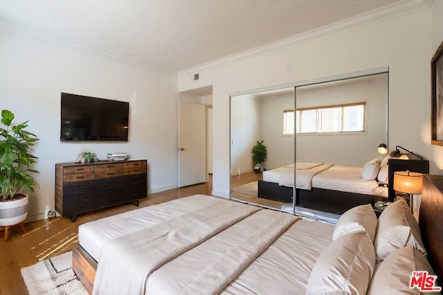 bedroom featuring hardwood / wood-style flooring, a closet, and crown molding