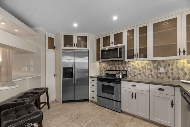 kitchen featuring backsplash, stainless steel appliances, white cabinetry, and light tile patterned flooring