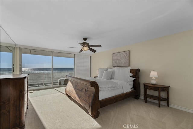 bedroom with access to exterior, ceiling fan, a water view, and light carpet