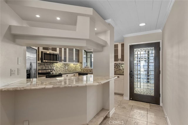 kitchen featuring kitchen peninsula, appliances with stainless steel finishes, decorative backsplash, light stone countertops, and white cabinetry