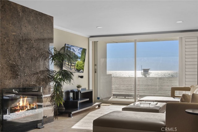 living room with a water view, light tile patterned floors, crown molding, and a premium fireplace