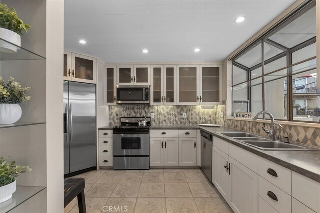 kitchen featuring tasteful backsplash, stainless steel appliances, sink, light tile patterned floors, and white cabinetry