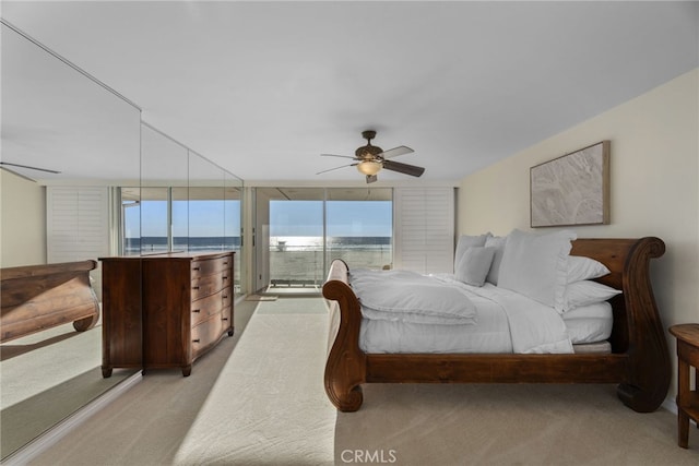 bedroom with access to exterior, ceiling fan, a water view, and light colored carpet