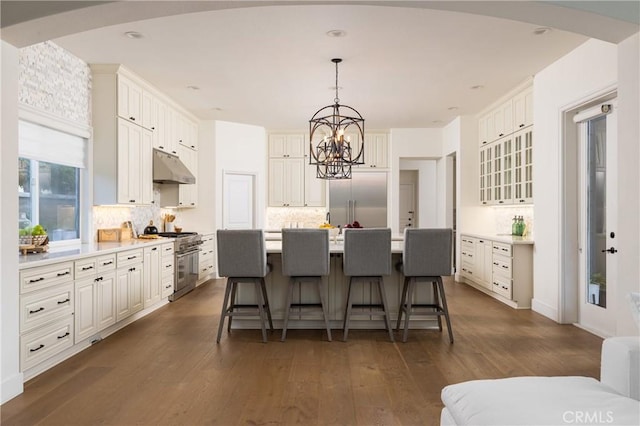 kitchen featuring decorative backsplash, dark hardwood / wood-style flooring, a center island with sink, high quality appliances, and white cabinets