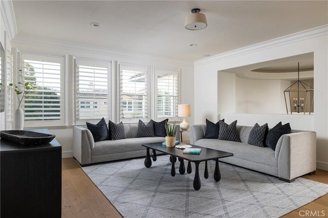 living room featuring light hardwood / wood-style floors, ornamental molding, and an inviting chandelier