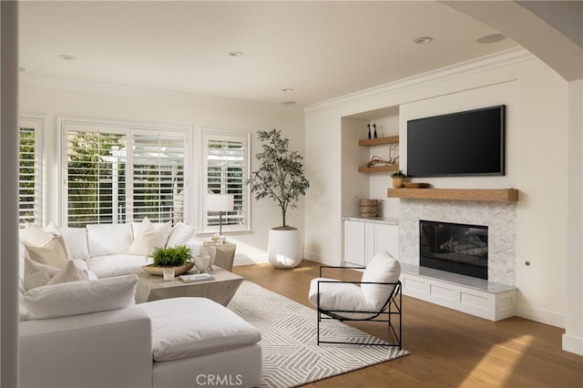 living room featuring a tile fireplace, crown molding, and dark wood-type flooring