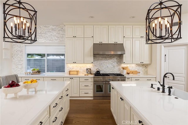 kitchen featuring light stone countertops, tasteful backsplash, decorative light fixtures, range with two ovens, and dark hardwood / wood-style floors