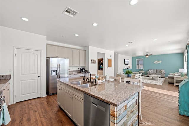 kitchen with stainless steel appliances, a sink, visible vents, open floor plan, and an island with sink