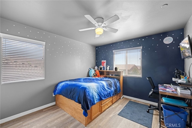 bedroom with light wood-type flooring, ceiling fan, and baseboards