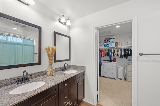 bathroom with visible vents, a sink, a spacious closet, and double vanity