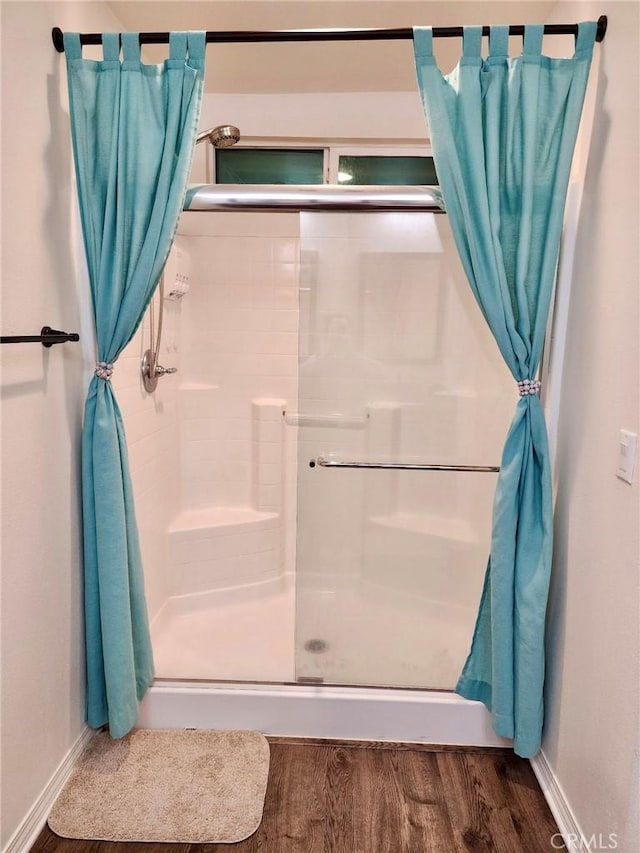 bathroom featuring a shower stall, baseboards, and wood finished floors