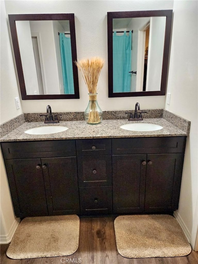 full bath featuring double vanity, a sink, and wood finished floors