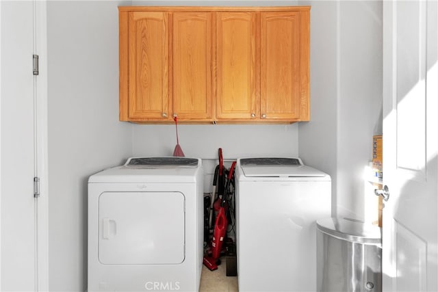 clothes washing area featuring separate washer and dryer and cabinets