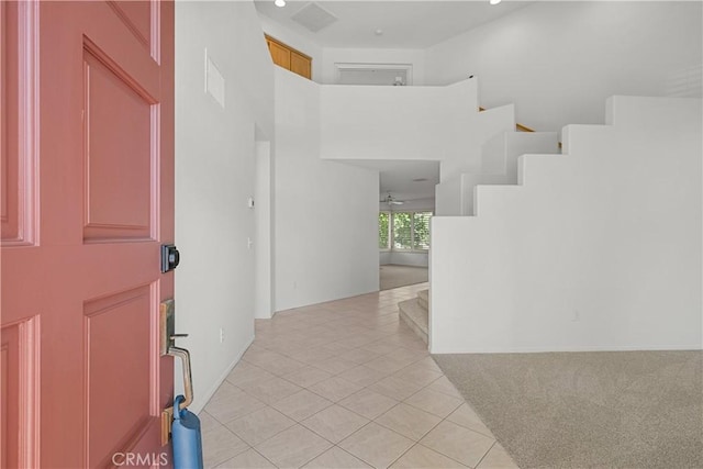 tiled foyer with ceiling fan and a towering ceiling