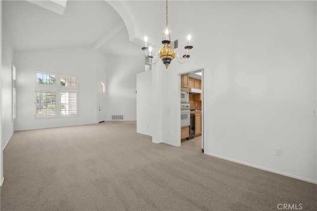 empty room featuring a notable chandelier, light colored carpet, beam ceiling, and high vaulted ceiling