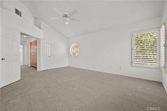 spare room with ceiling fan, light colored carpet, and vaulted ceiling