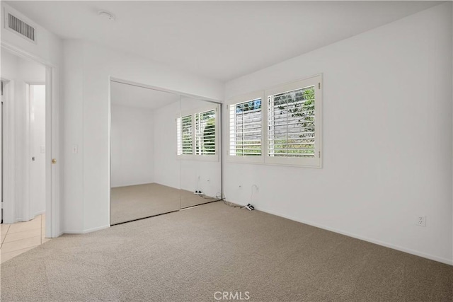 unfurnished bedroom featuring a closet and light colored carpet