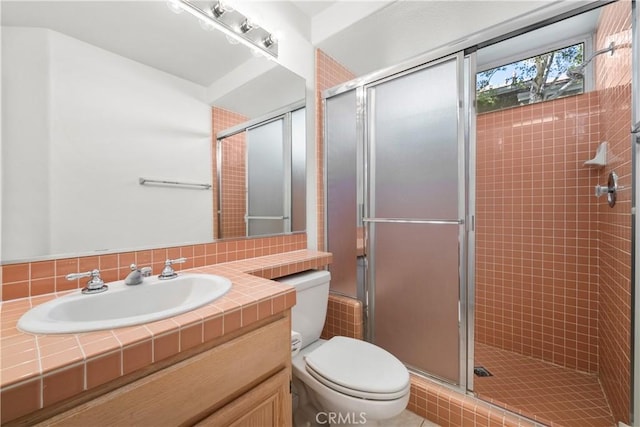 bathroom with toilet, a shower with door, and vanity