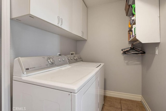 laundry room featuring separate washer and dryer, light tile patterned floors, and cabinets