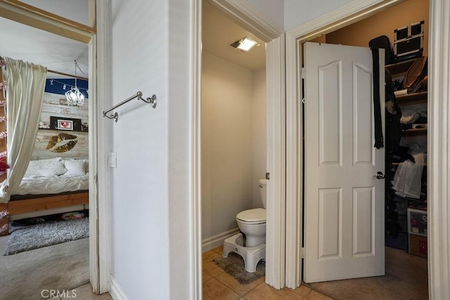 bathroom with toilet, an inviting chandelier, and tile patterned floors