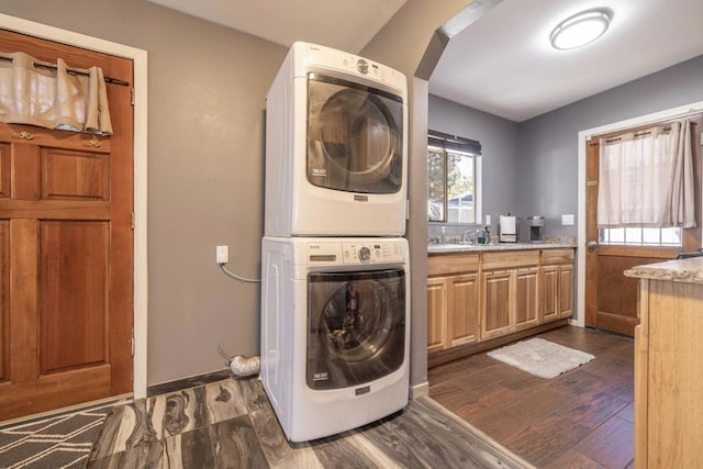 laundry room with cabinets, stacked washer and clothes dryer, and dark hardwood / wood-style floors