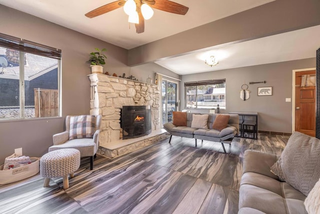 living room with vaulted ceiling with beams, ceiling fan, wood-type flooring, and a wood stove