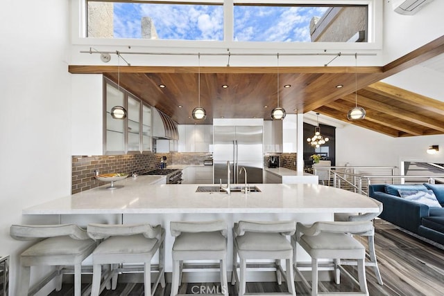 kitchen featuring tasteful backsplash, kitchen peninsula, sink, premium appliances, and wooden ceiling