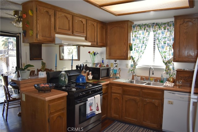 kitchen with ceiling fan, sink, kitchen peninsula, dark wood-type flooring, and appliances with stainless steel finishes