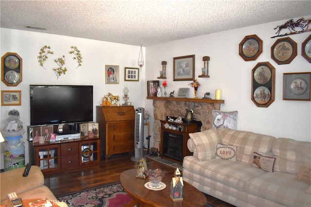 living room with a textured ceiling, a fireplace, and dark hardwood / wood-style flooring