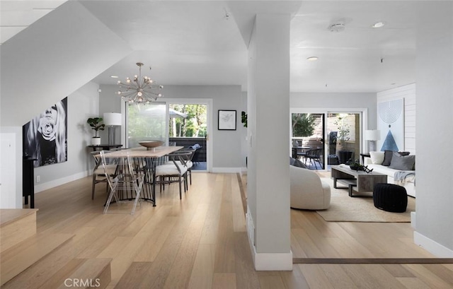 living room featuring vaulted ceiling, an inviting chandelier, and light hardwood / wood-style floors