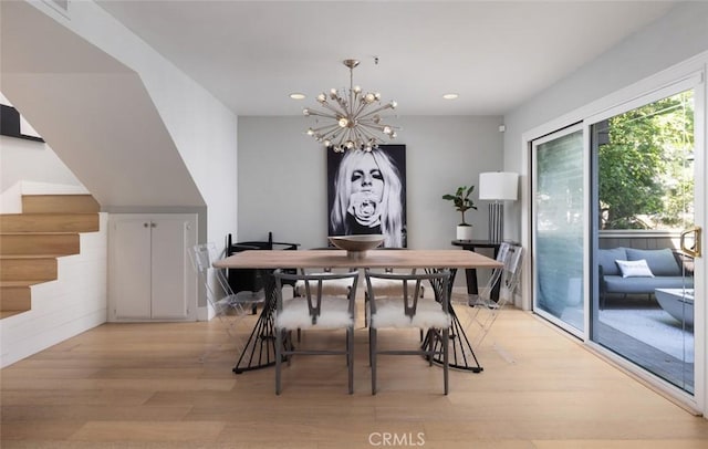 dining area with light hardwood / wood-style floors and a chandelier