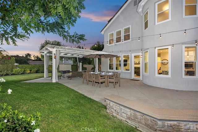 back house at dusk with a yard, a pergola, and a patio area