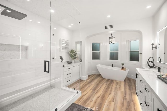 bathroom with shower with separate bathtub, hardwood / wood-style floors, and vanity