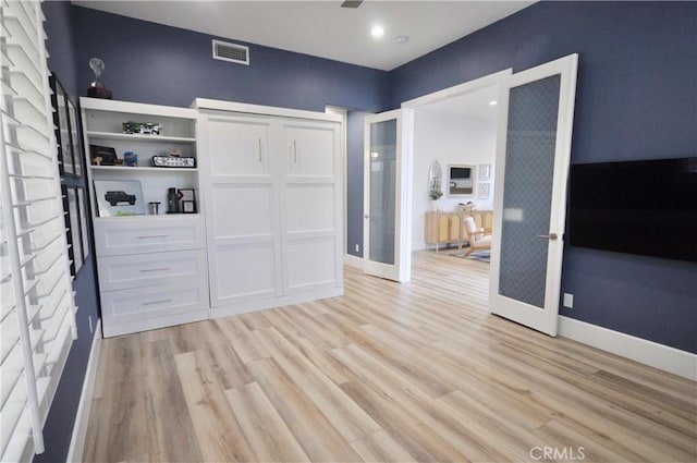 unfurnished bedroom featuring a closet, light hardwood / wood-style floors, and french doors