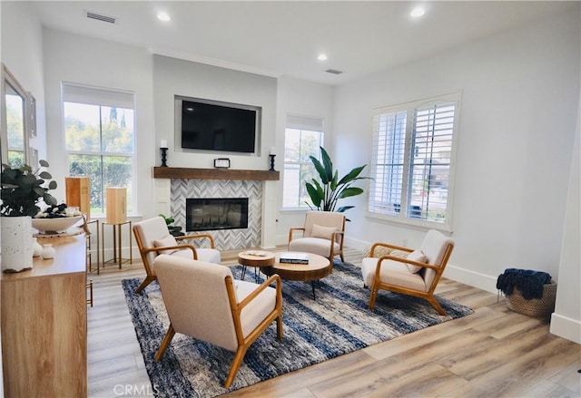 living room featuring a tile fireplace, plenty of natural light, and light hardwood / wood-style flooring