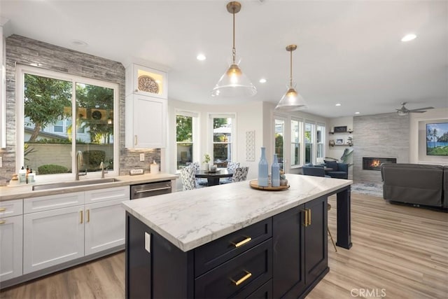 kitchen featuring sink, white cabinetry, a center island, pendant lighting, and decorative backsplash