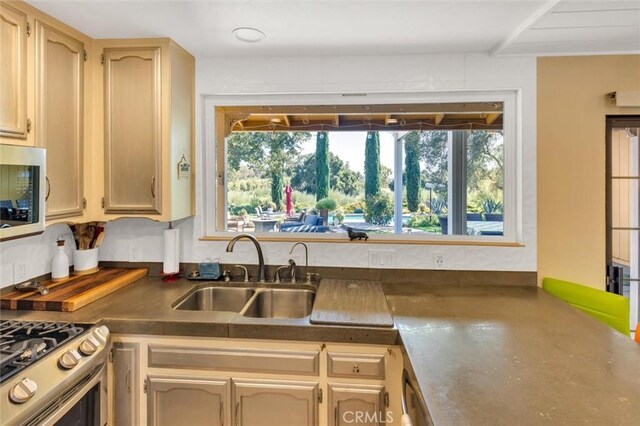 kitchen with range, light brown cabinets, and sink